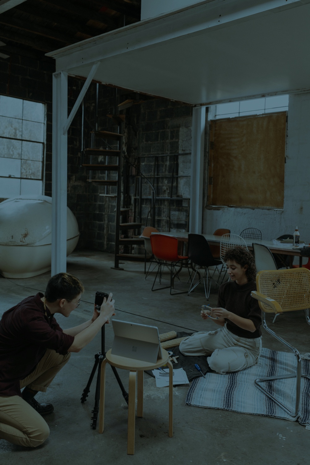 Photographie de deux personnes dans un loft industriel, l'une prenant une photo de l'autre.
